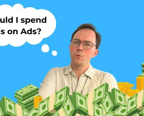 Simon, surrounded by piles of cash, asks the question, "Should I spend this all on ads?"